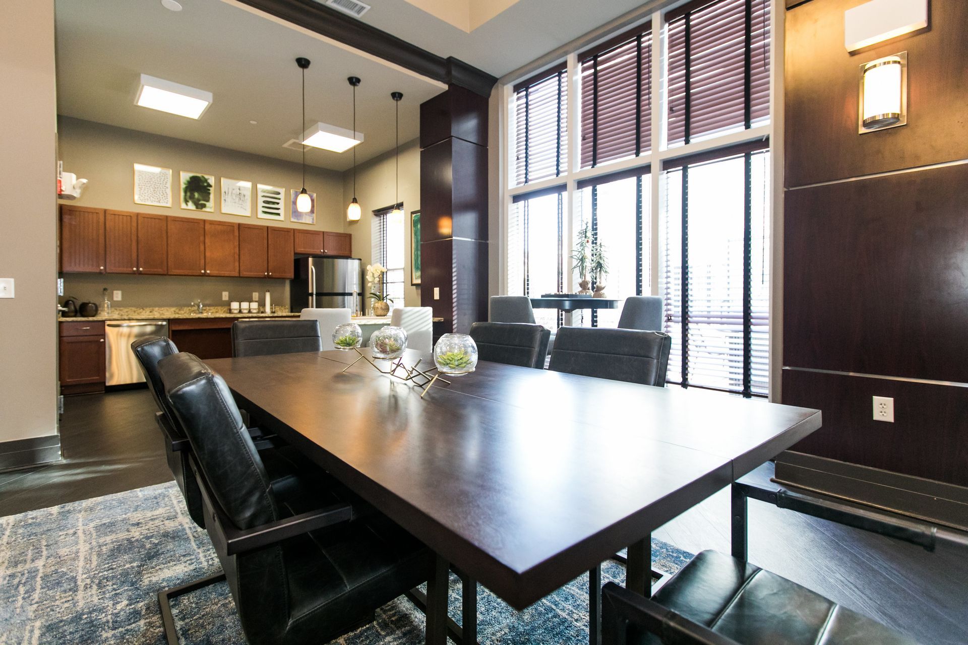 Modern dining room with dark wood table, black chairs, and large windows with blinds at Verde at Howard Square West Apartments in Elkridge, MD.