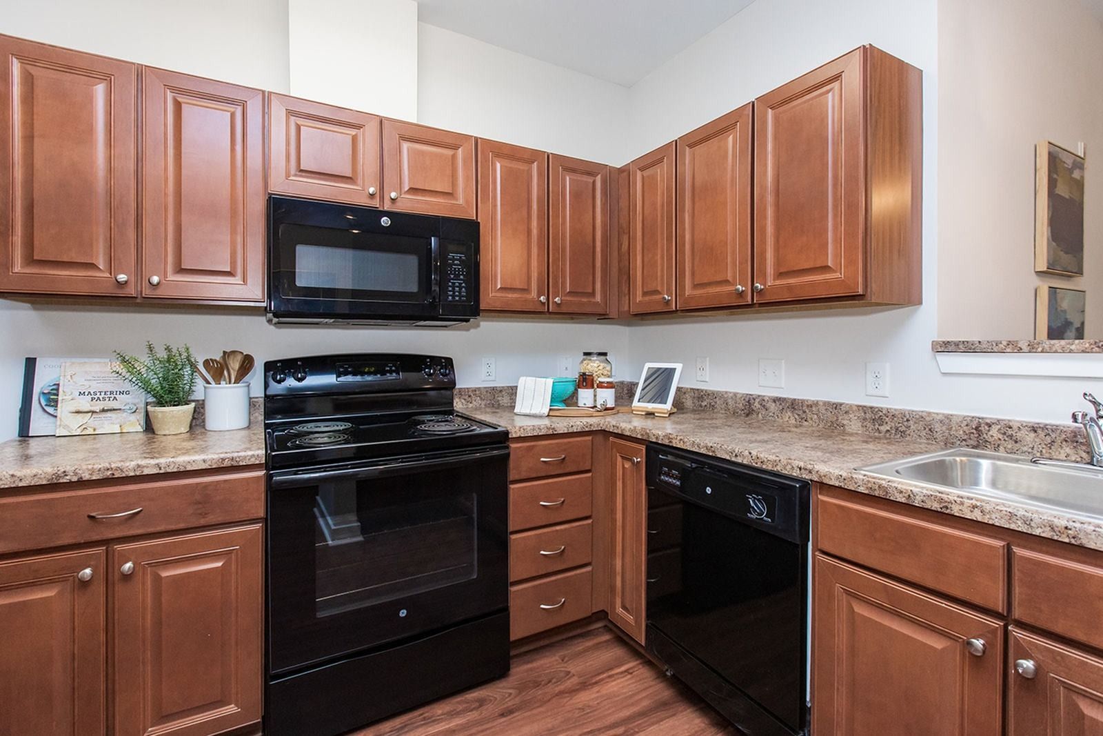 Apartment kitchen with wood cabinets, dark appliances, and granite countertops at Verde at Howard Square West Apartments in Elkridge, MD.