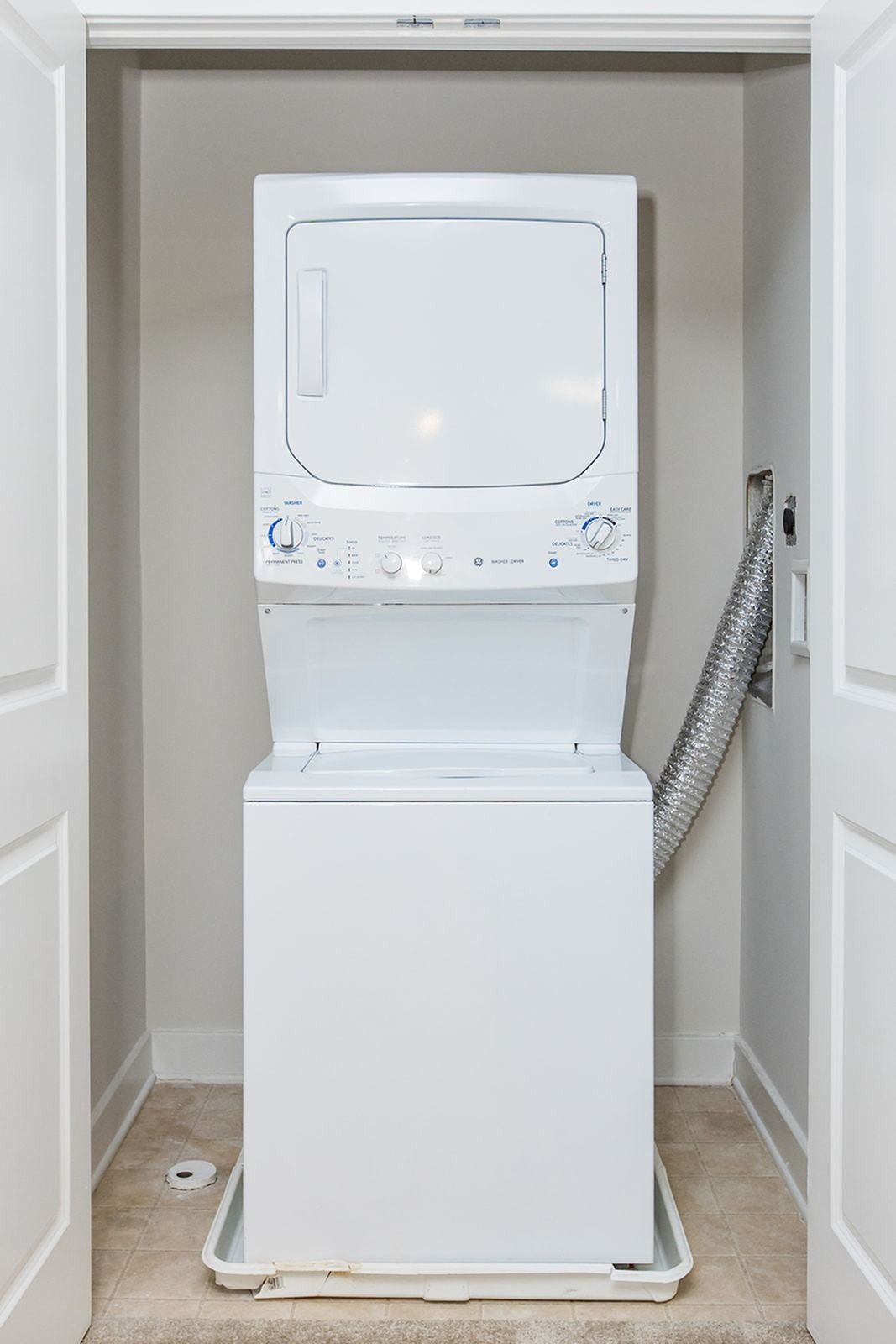 White stacked washer and dryer in a closet with open doors at Verde at Howard Square West Apartments in Elkridge, MD.