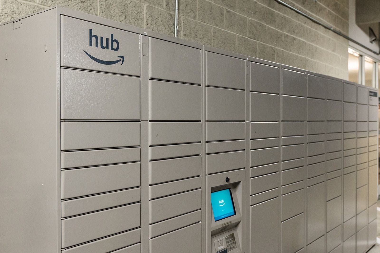 Row of white Amazon Hub lockers with a blue touchscreen kiosk in a hallway at Verde at Howard Square West Apartments in Elkridge, MD.