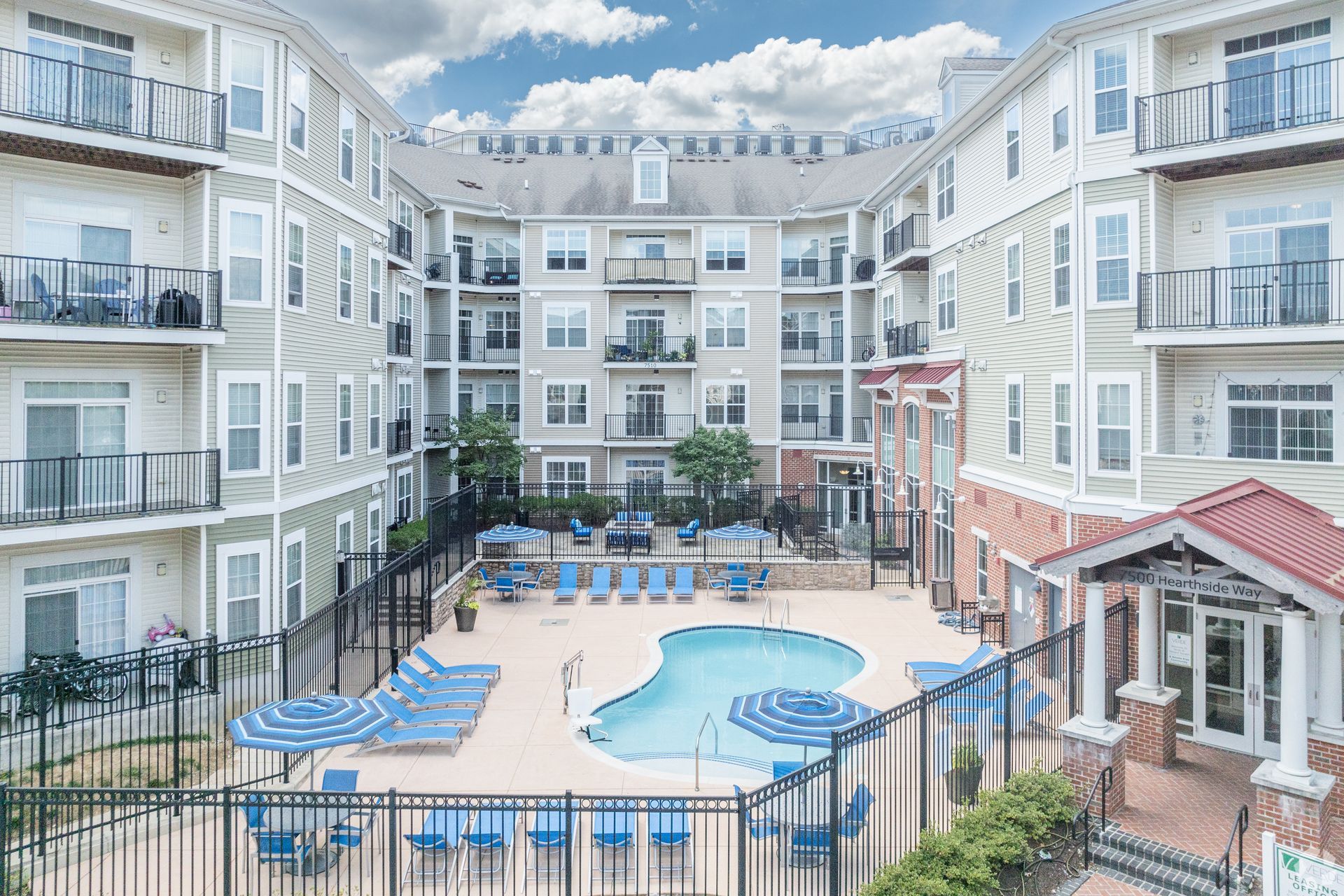 Outdoor swimming pool with lounge chairs surrounded by apartment buildings at Verde at Howard Square West Apartments in Elkridge, MD.