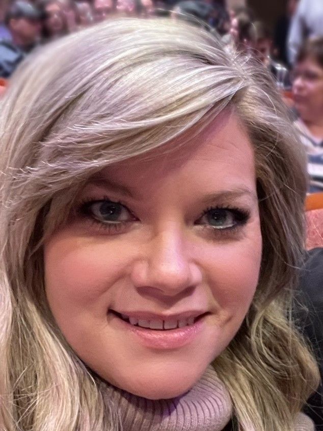 A close up of a woman 's face smiling while sitting in a chair.