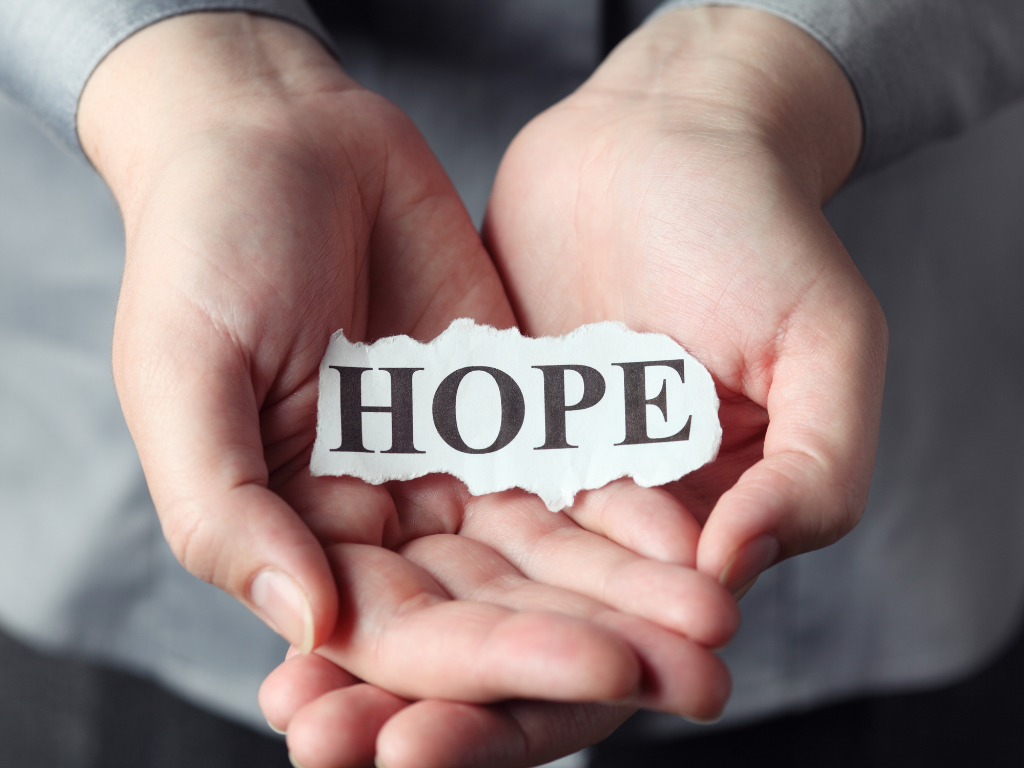 Hands cupped, holding a torn piece of paper with the word 