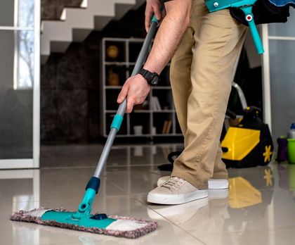 A man is cleaning the floor with a mop.