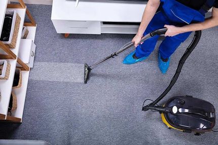 A person is using a vacuum cleaner to clean a carpet in a living room.
