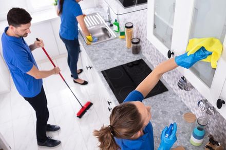 A group of people are cleaning a kitchen together.