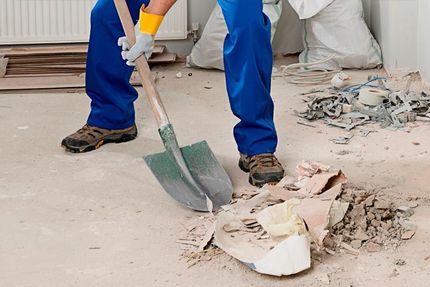A man is using a shovel to clean up a mess on the floor.