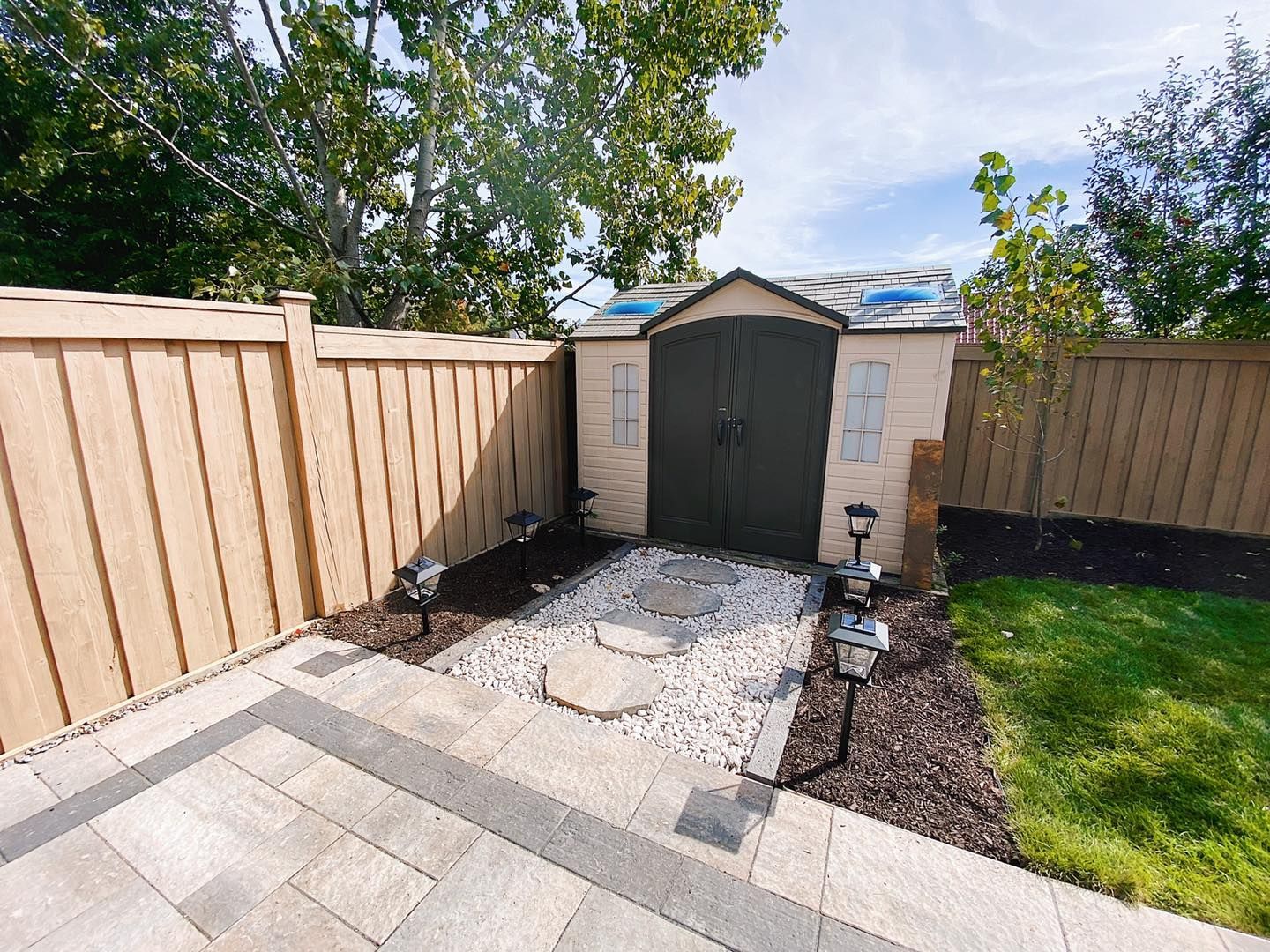 There is a shed in the backyard with a wooden fence around it.