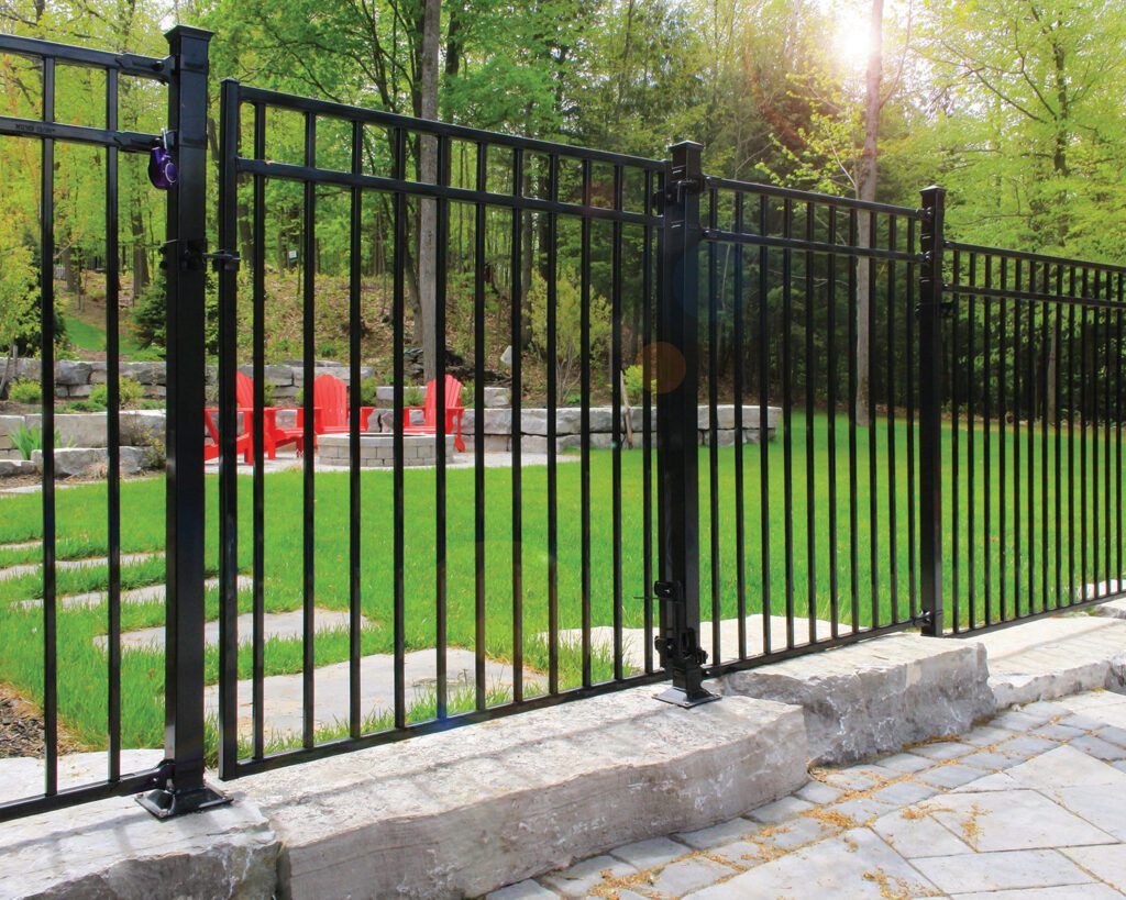 A black metal fence surrounds a lush green field.