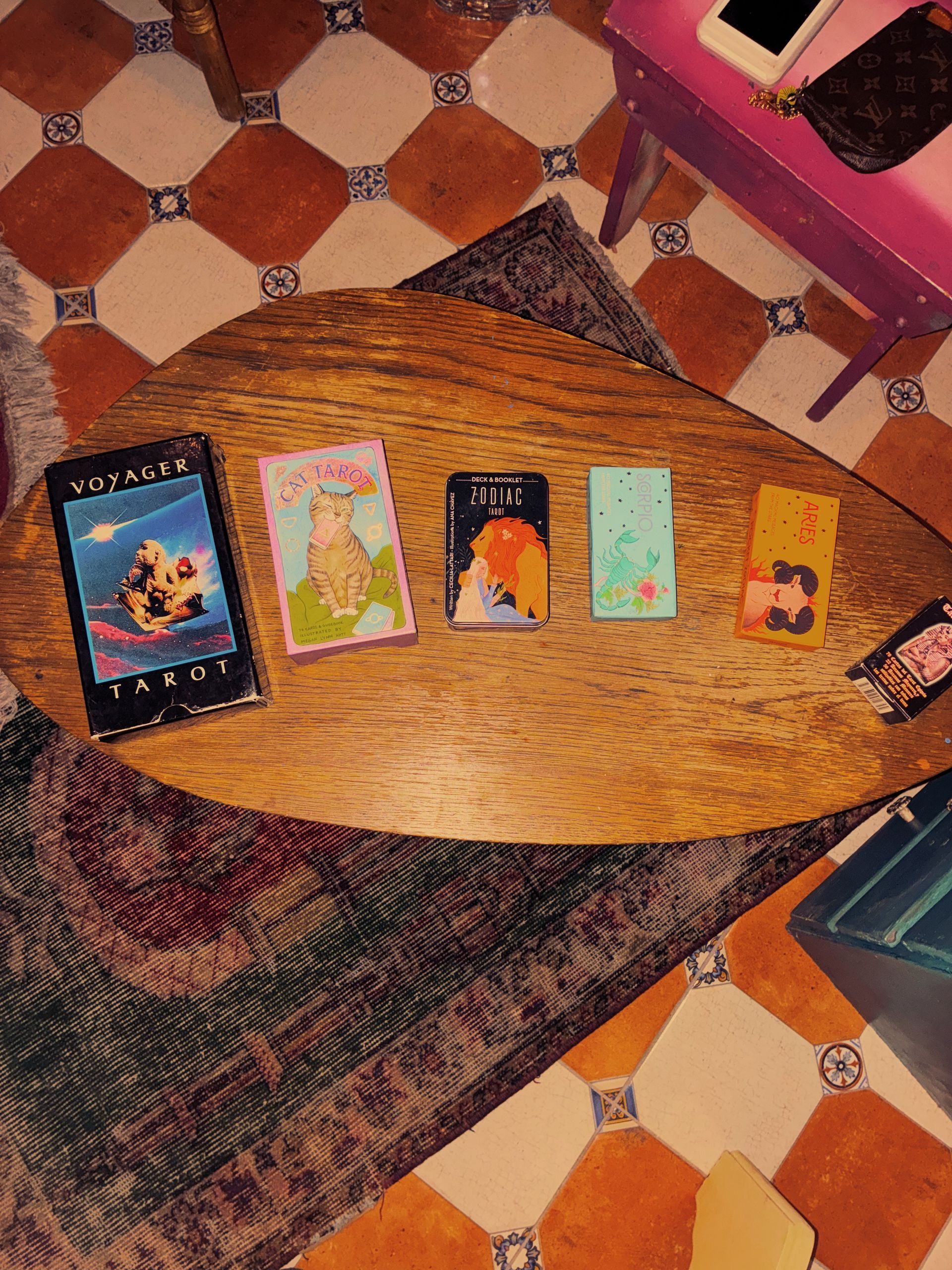 Five tarot-style cards arranged on a wooden table with patterned tile flooring in the background