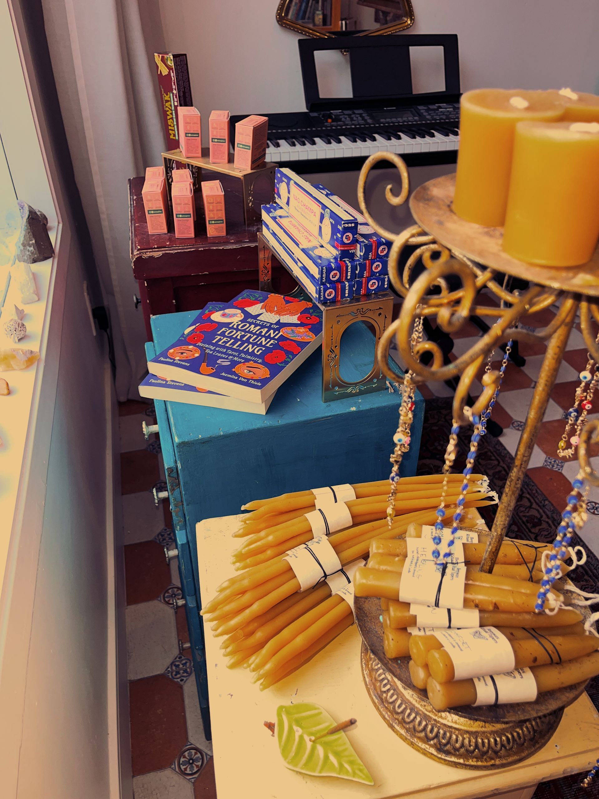 Decorative table with candles, books, and a tray of cinnamon sticks on a teal cloth