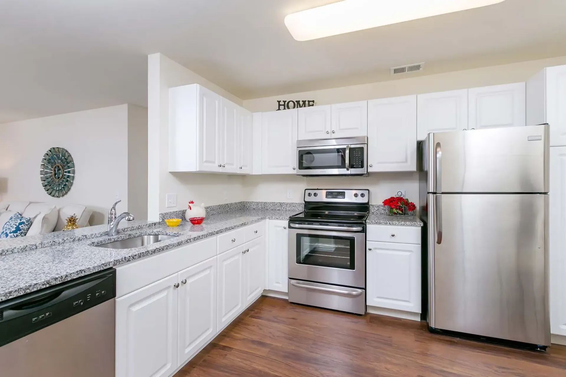 Bright white kitchen with granite counters, white cabinets, and stainless steel appliances.