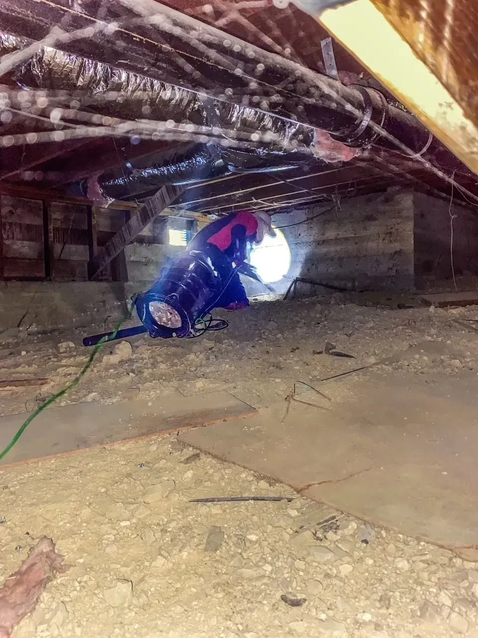A man is crawling through a hole in the ceiling of a building.