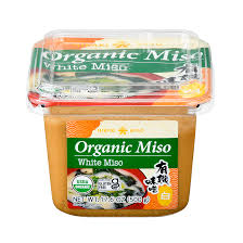 A container of organic miso white miso on a white background.
