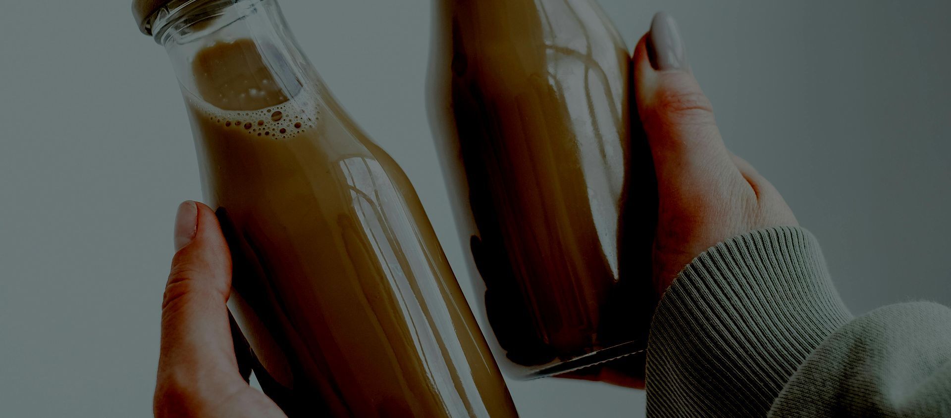 A person is holding two bottles of milk in their hands.