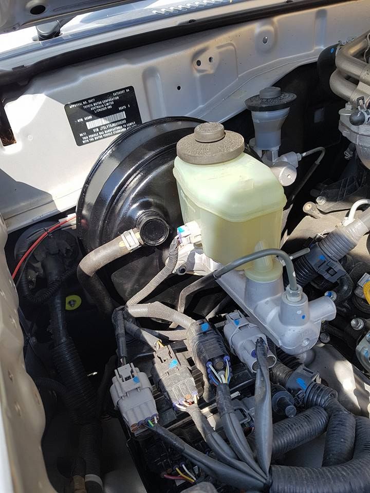 A close up of a car engine with a brake fluid tank.