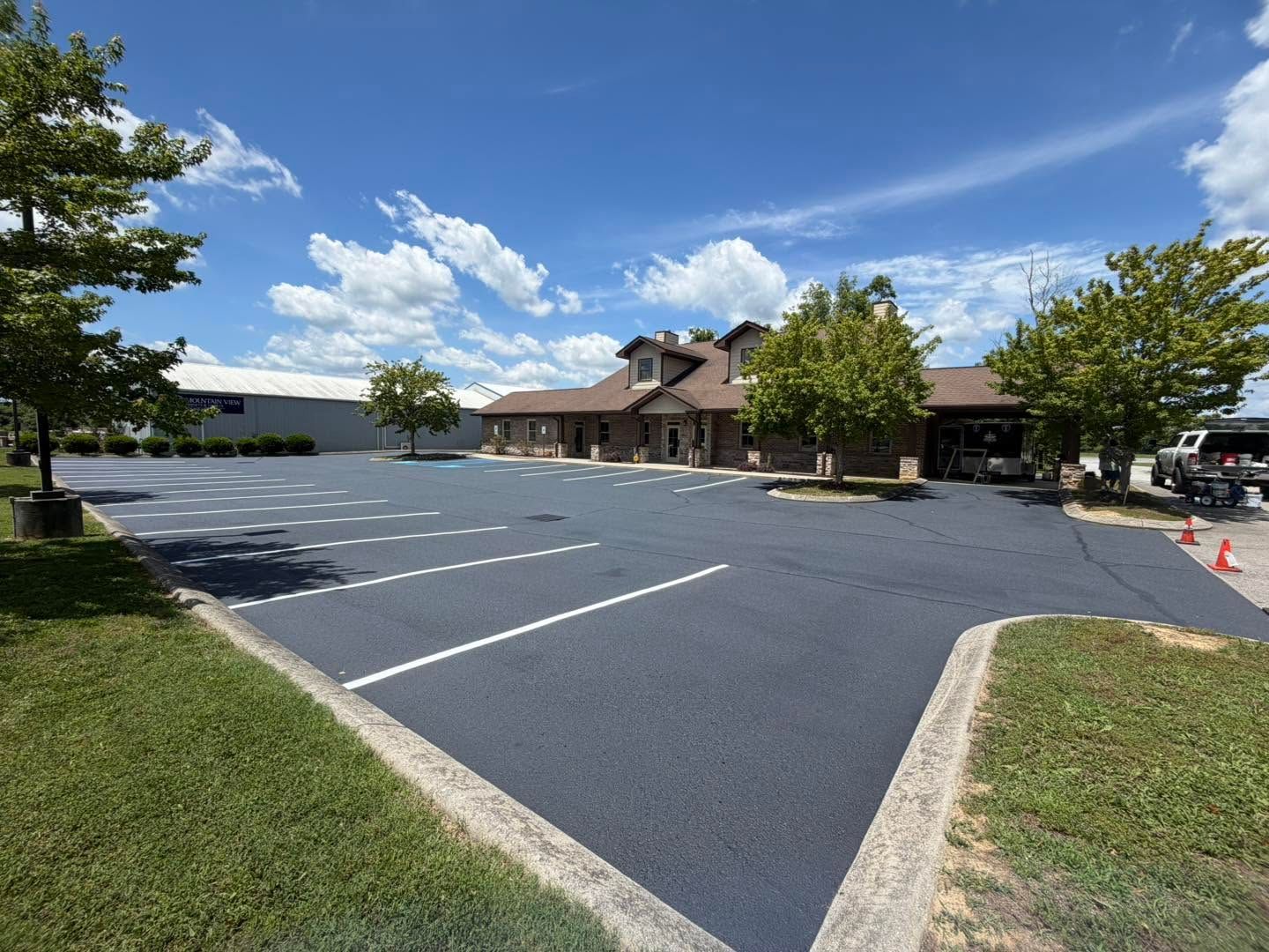 Exterior view of a dark asphalt parking lot in front of a brick building with a church steeple.