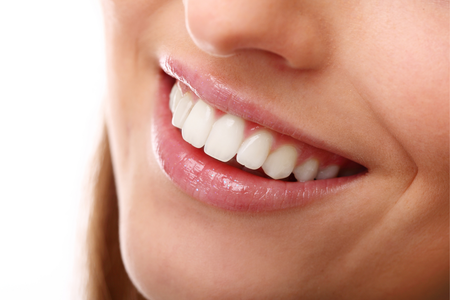 Close-up of a person smiling, showing straight, white teeth and lips.