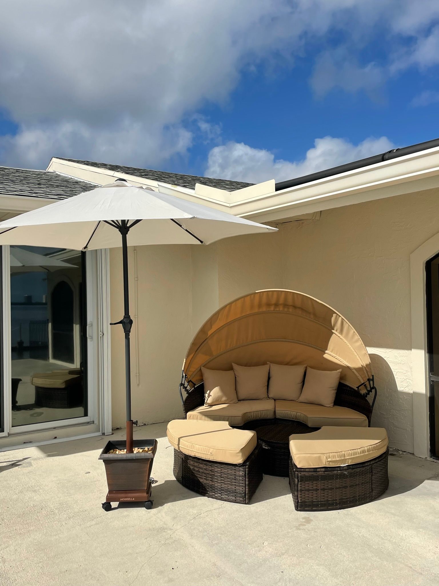 A patio with a couch and an umbrella in front of a house