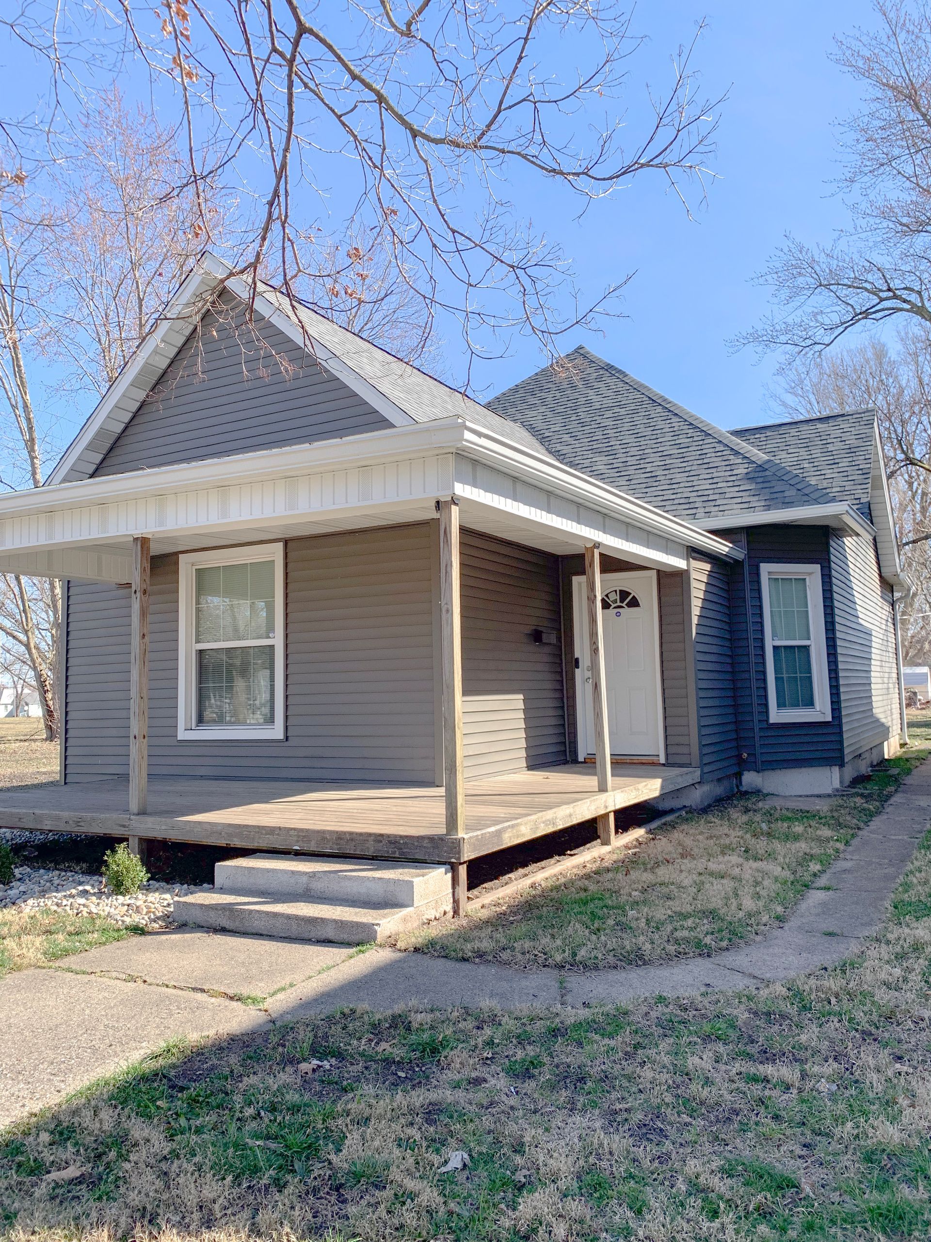A small house with a porch and a blue sky in the background.