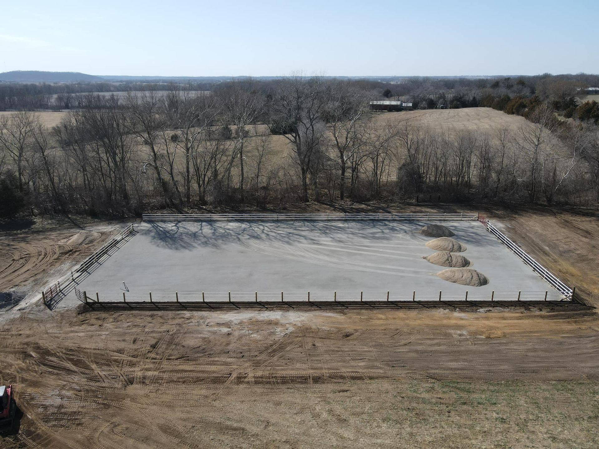 Concrete foundation slab under construction in a rural field with trees in the background