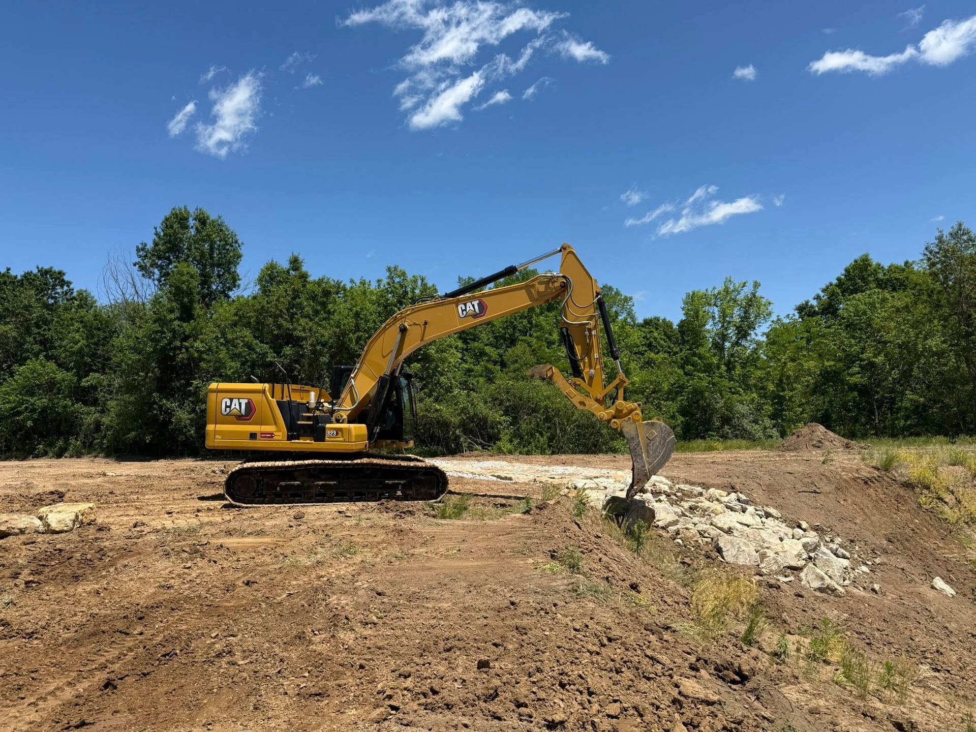 Yellow excavator digging dirt at a construction site under a blue sky
