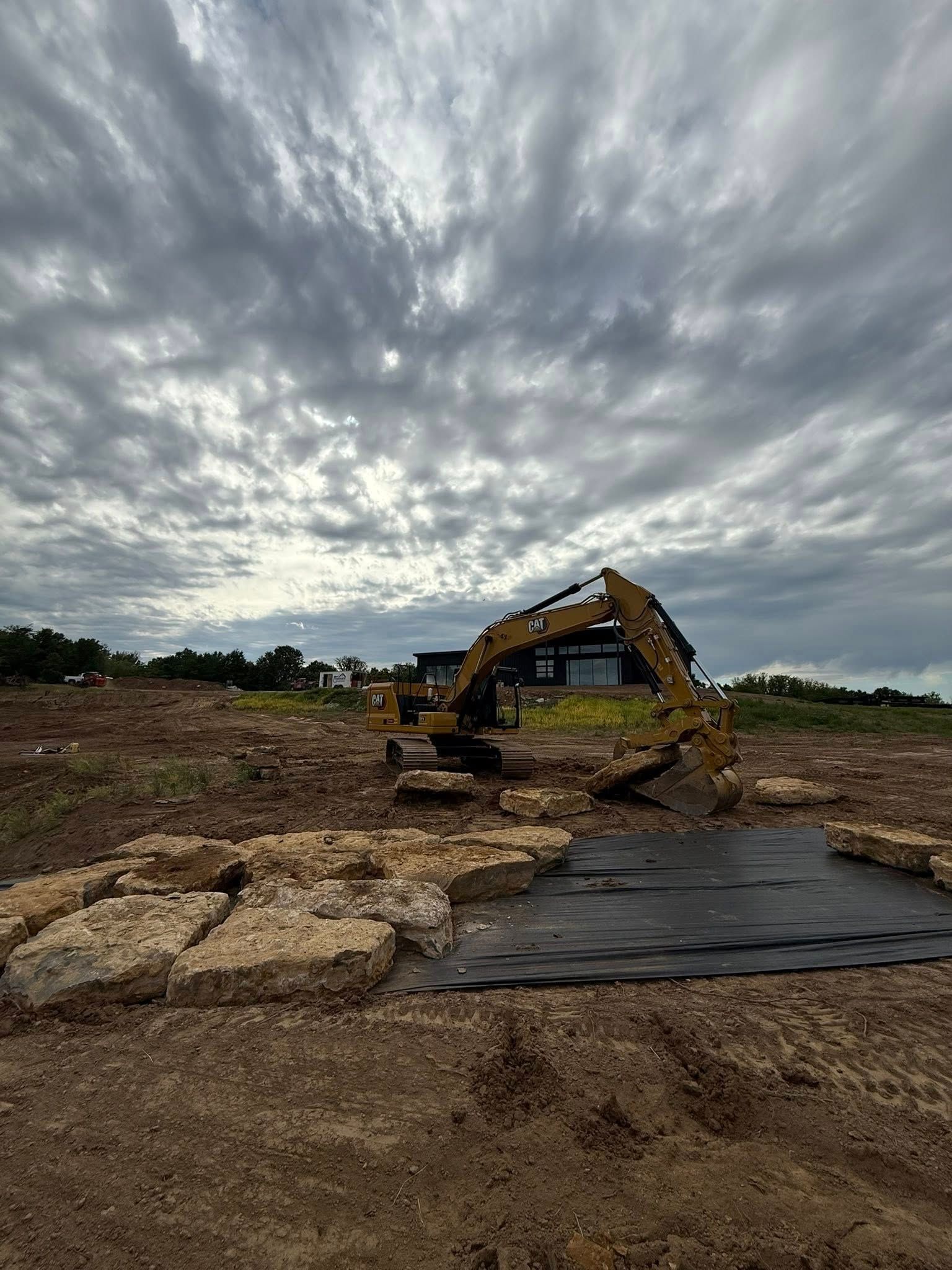 Yellow excavator on a muddy construction site under a cloudy sky