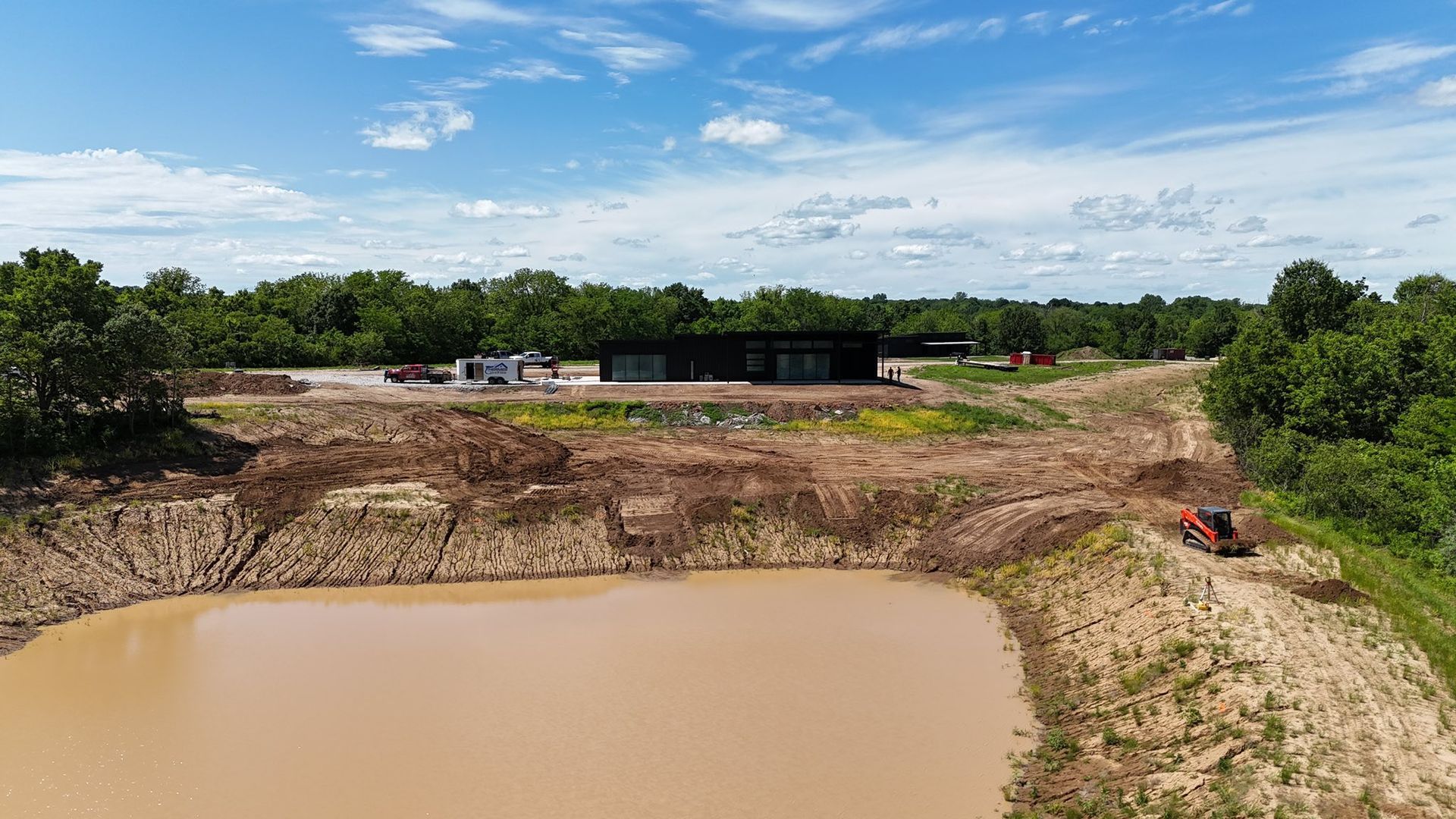 Mud pit at a construction site with excavators and dirt mounds under a blue sky