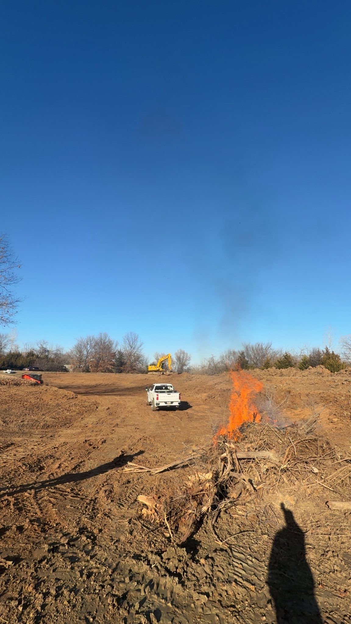 Dirt construction site with a white truck, orange marker line, and clear blue sky