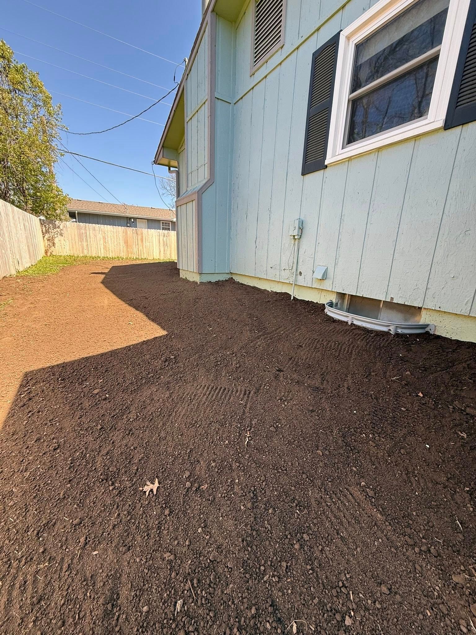 Gravel path beside a pale blue house with white-trimmed windows and string lights overhead