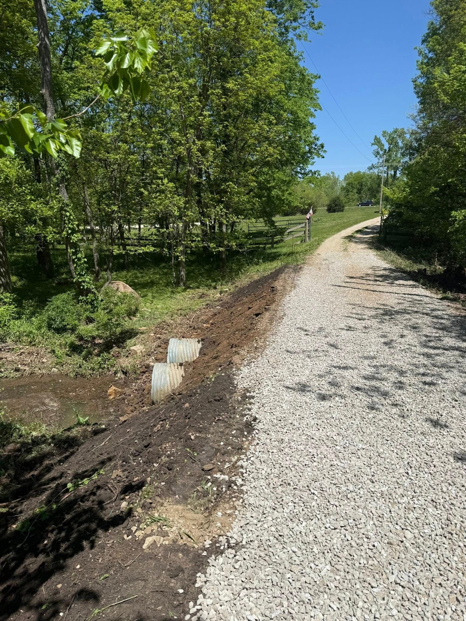 Gravel path beside leafy green trees under a clear blue sky