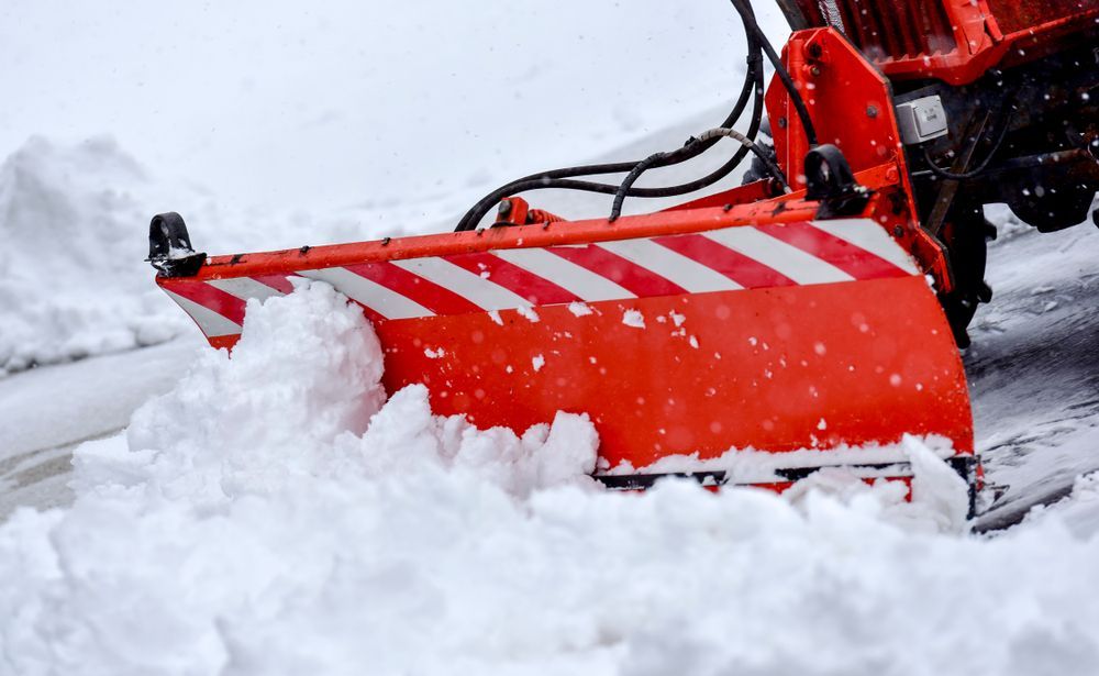 Red snowblower clearing thick snow, with snow piled in front of its red plow.