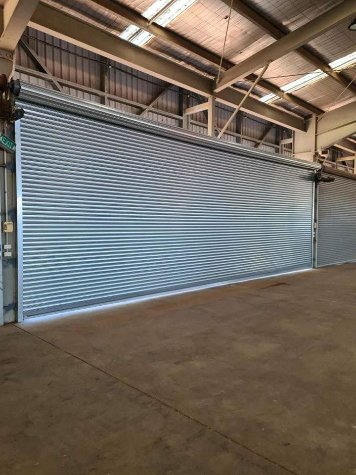 A large warehouse with a lot of rolling shutters on the doors.