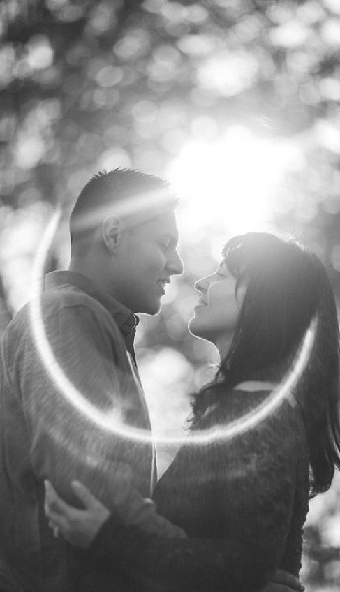 Couple embracing, looking at each other. Sunlight flares around them, black and white.