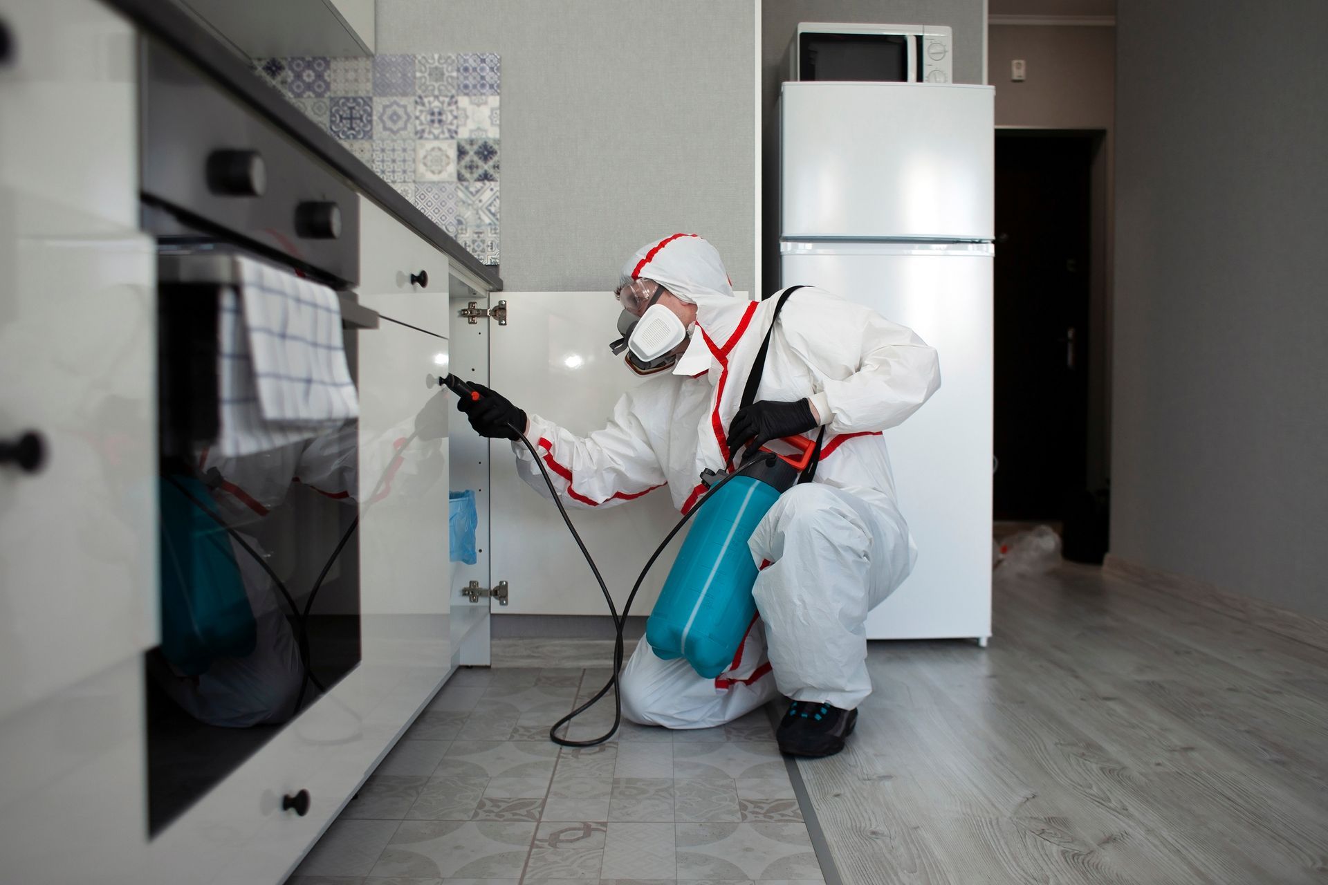 Worker in a protective suit performing pest control services, treating a home for insects safely.