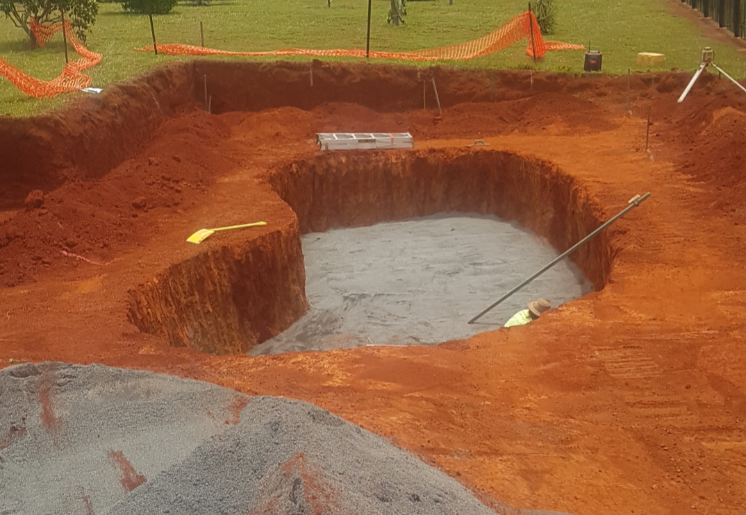 A dug-out hole for a pond, with red soil surrounding it. — Snell Earthworx In Craignish, QLD