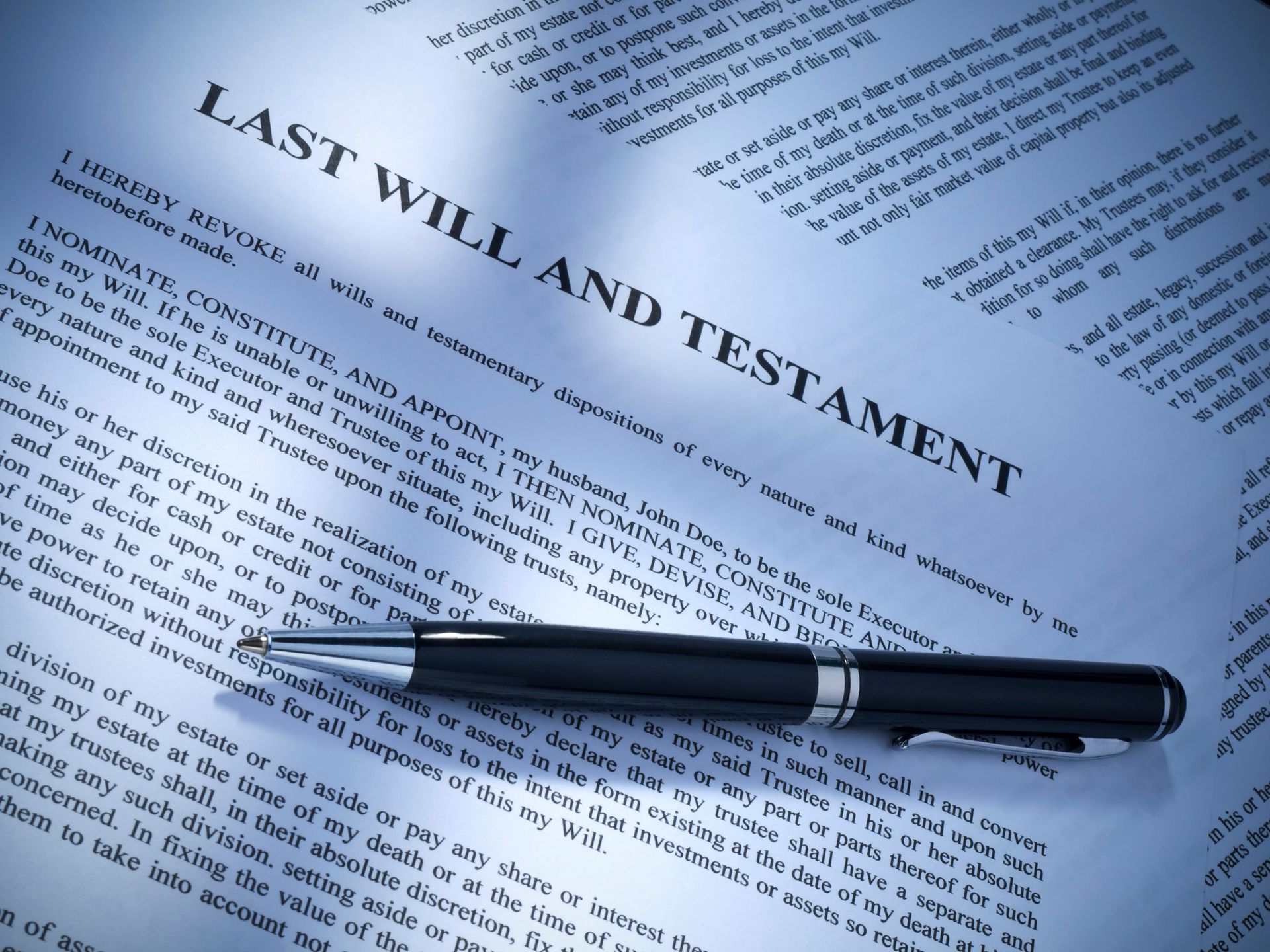 A black ballpoint pen resting across the title Last Will and Testament on a printed legal document.