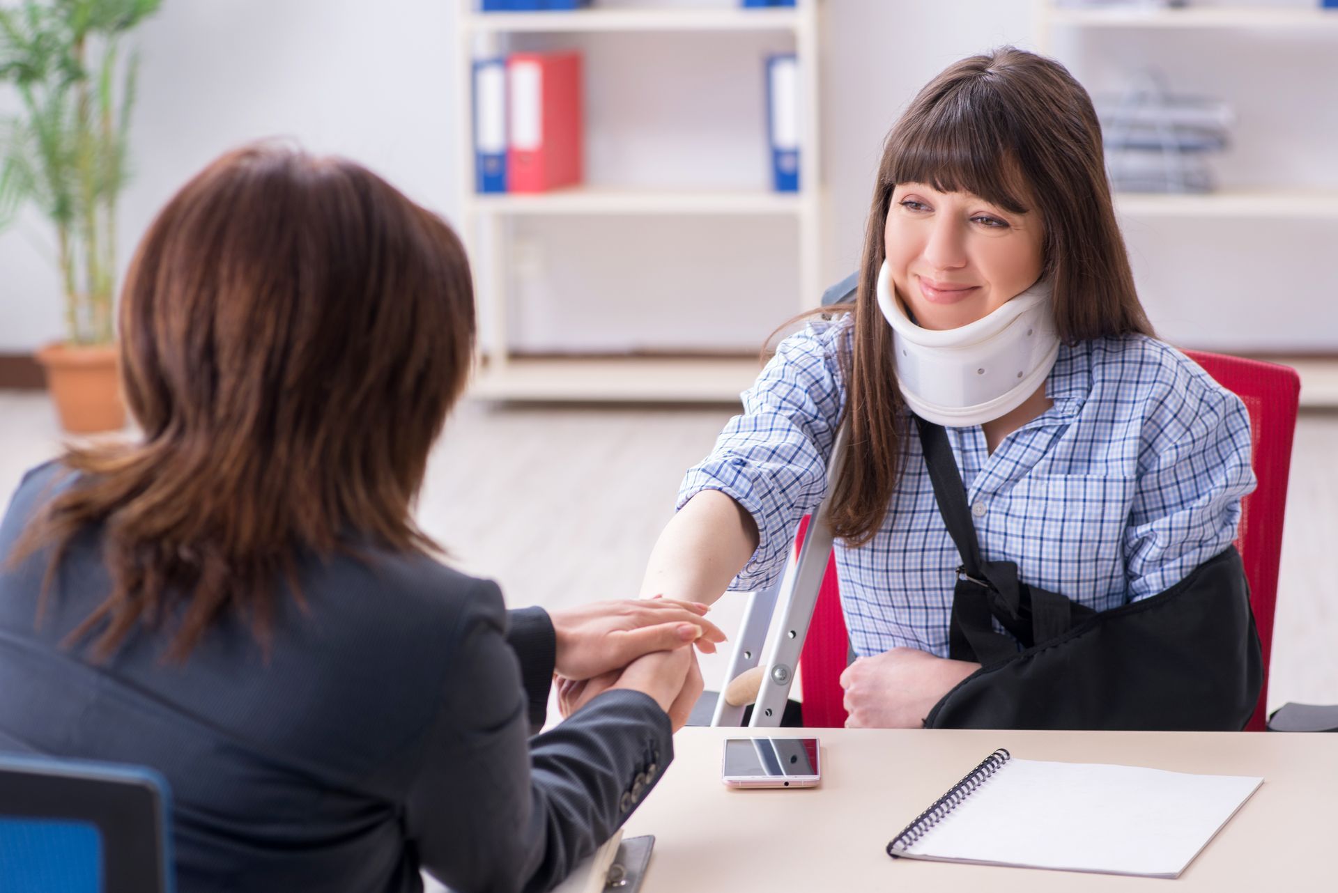 A lawyer is holding the hand of her injured client.