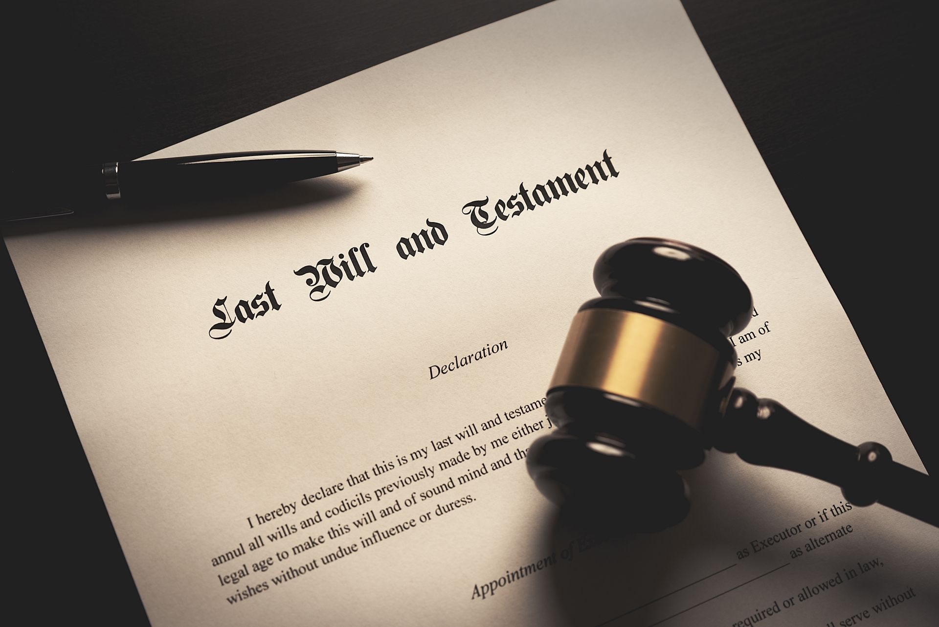 A wooden gavel and a fountain pen rest on top of a legal document titled Last Will and Testament. A wooden gavel and a fountain pen rest on top of a legal document titled Last Will and Testament.