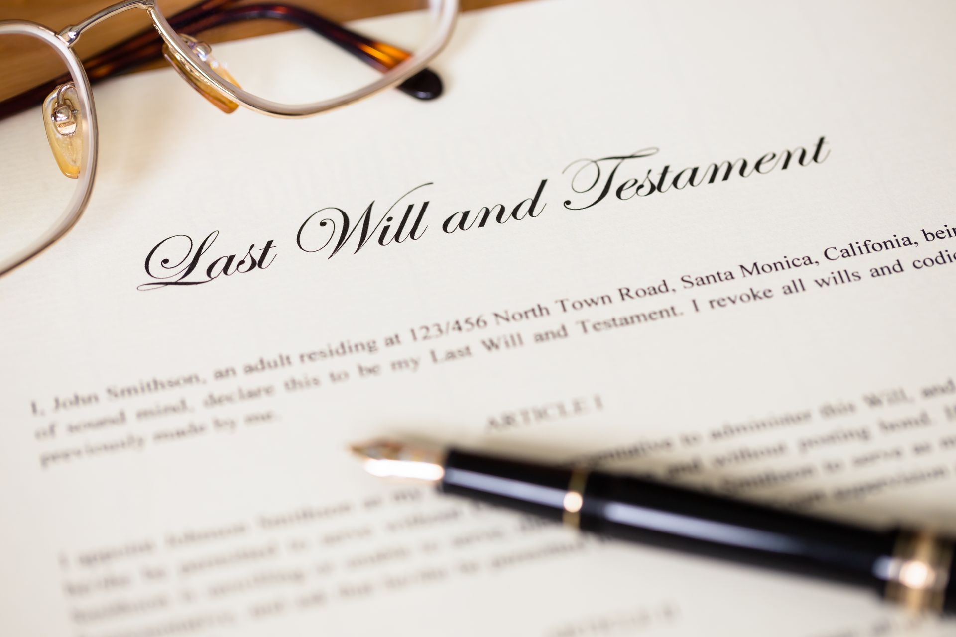 A fountain pen resting on a Last Will and Testament document next to a pair of eyeglasses.