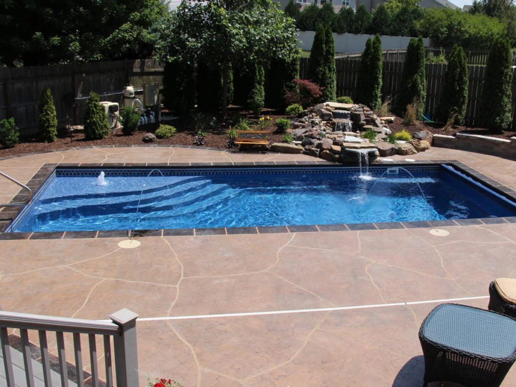 A large swimming pool with a waterfall in the backyard