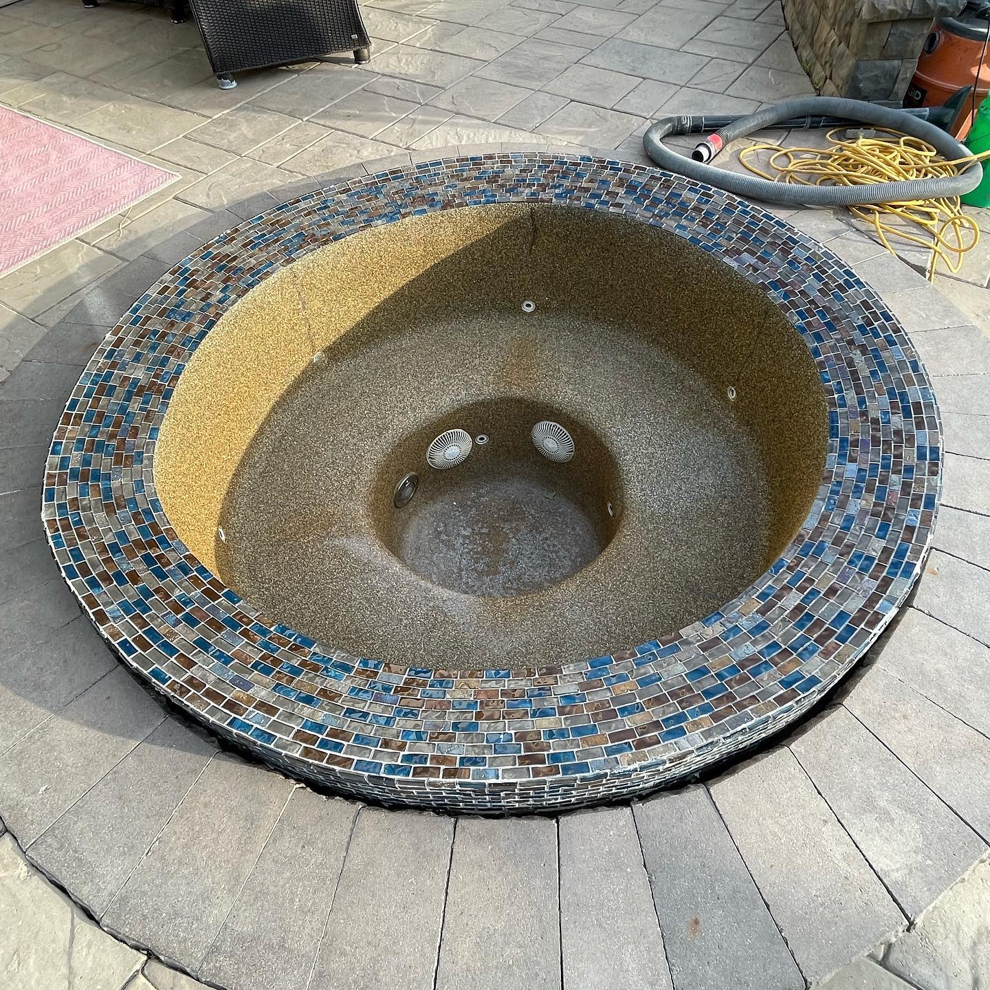 Mosaic public sink with blue, tan, and brown tiles on a paved sidewalk