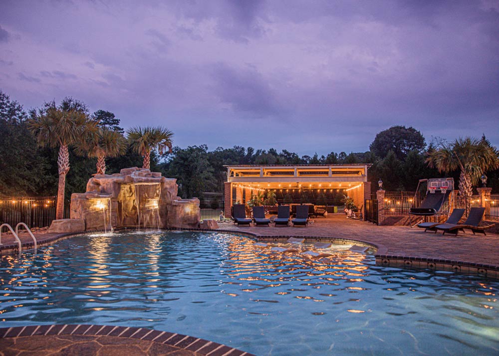 There is a large swimming pool with a waterfall in the background.
