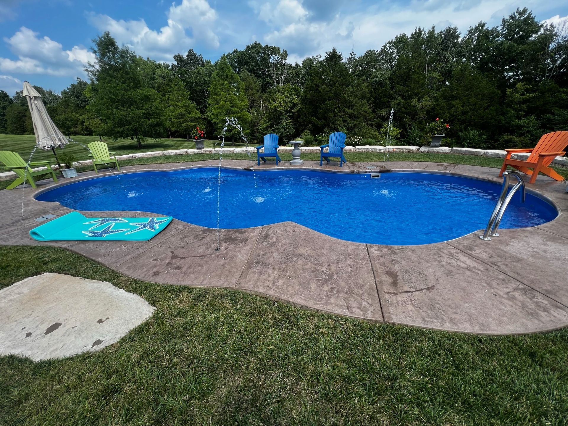 Backyard swimming pool with blue water, lounge chairs, and a slide on a sunny day