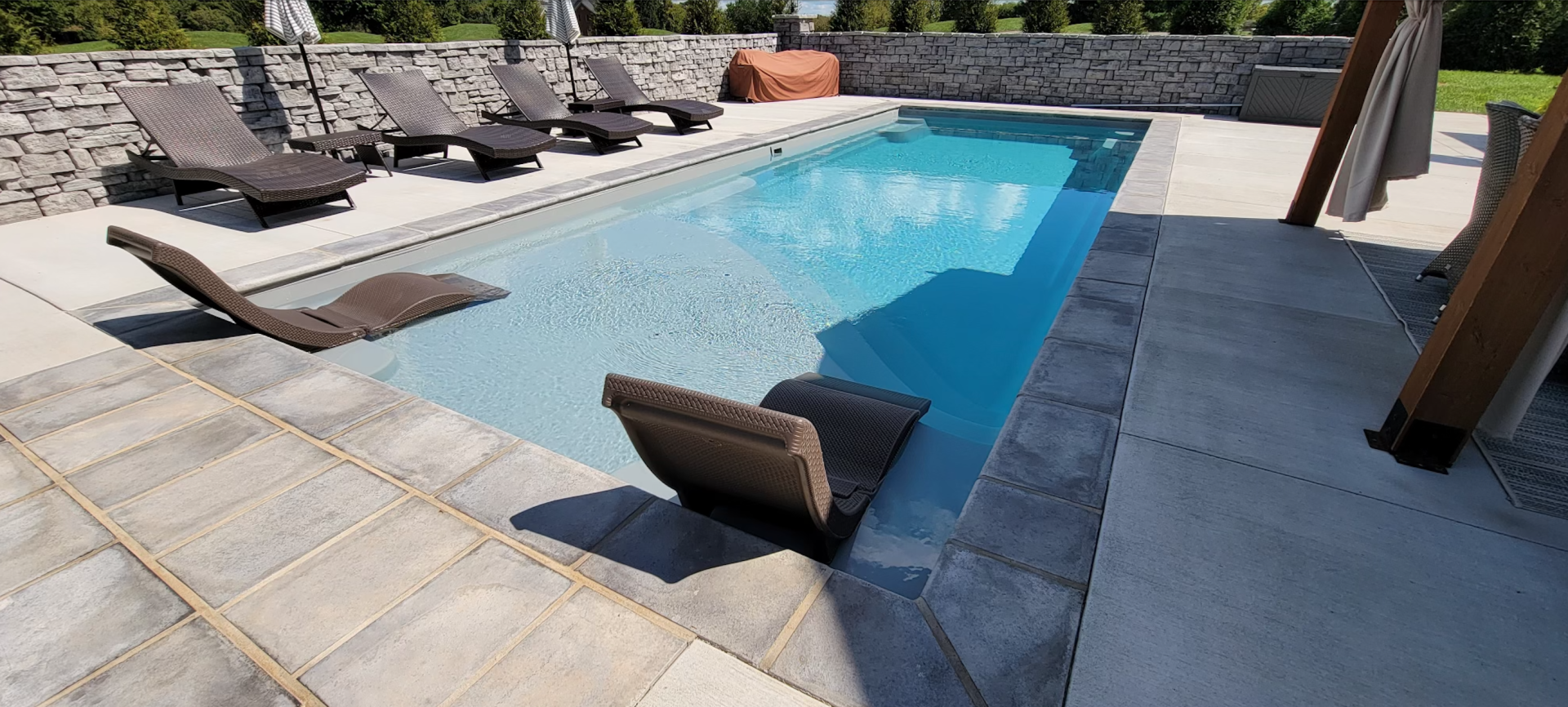 A large swimming pool surrounded by lawn chairs and umbrellas.