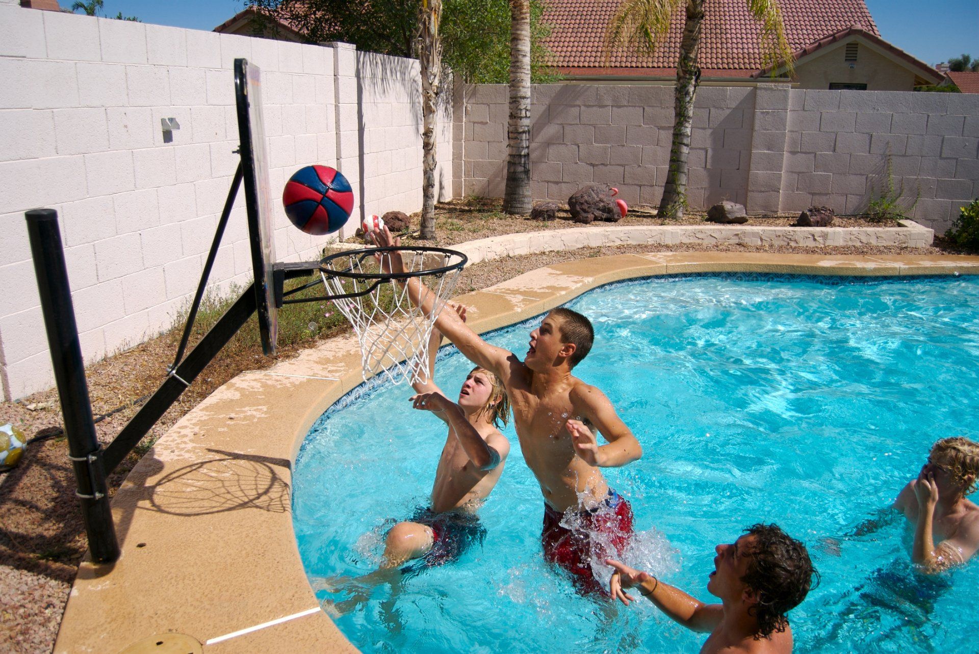 A group of children are playing basketball in a swimming pool