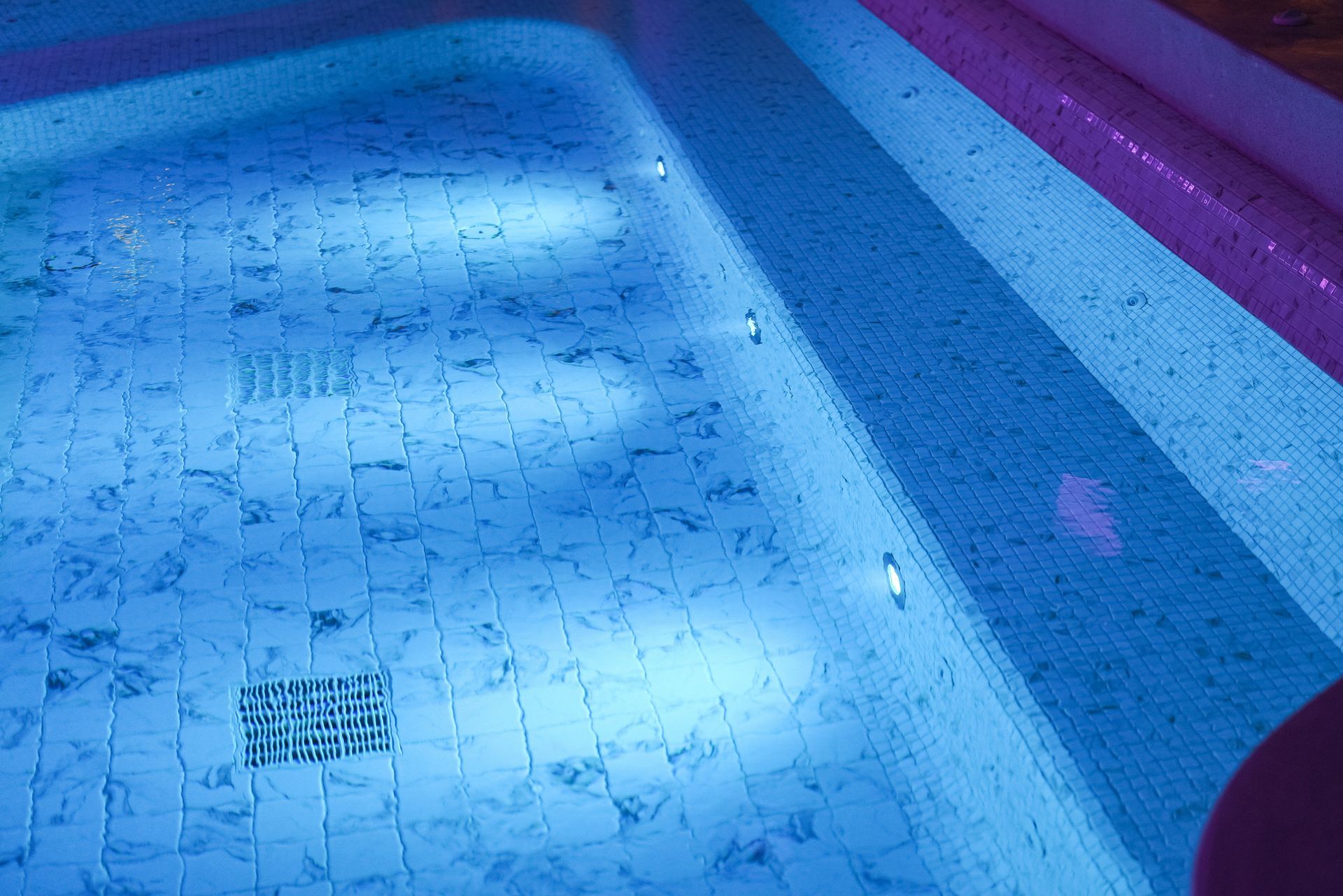 Blue-tinted shallow pool with tiled floor and floating lane divider ropes