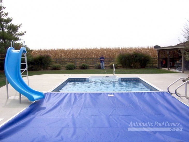 A pool with a blue cover and a blue slide