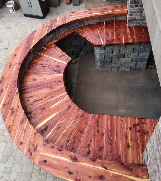 A wooden bench with a brick wall in the background