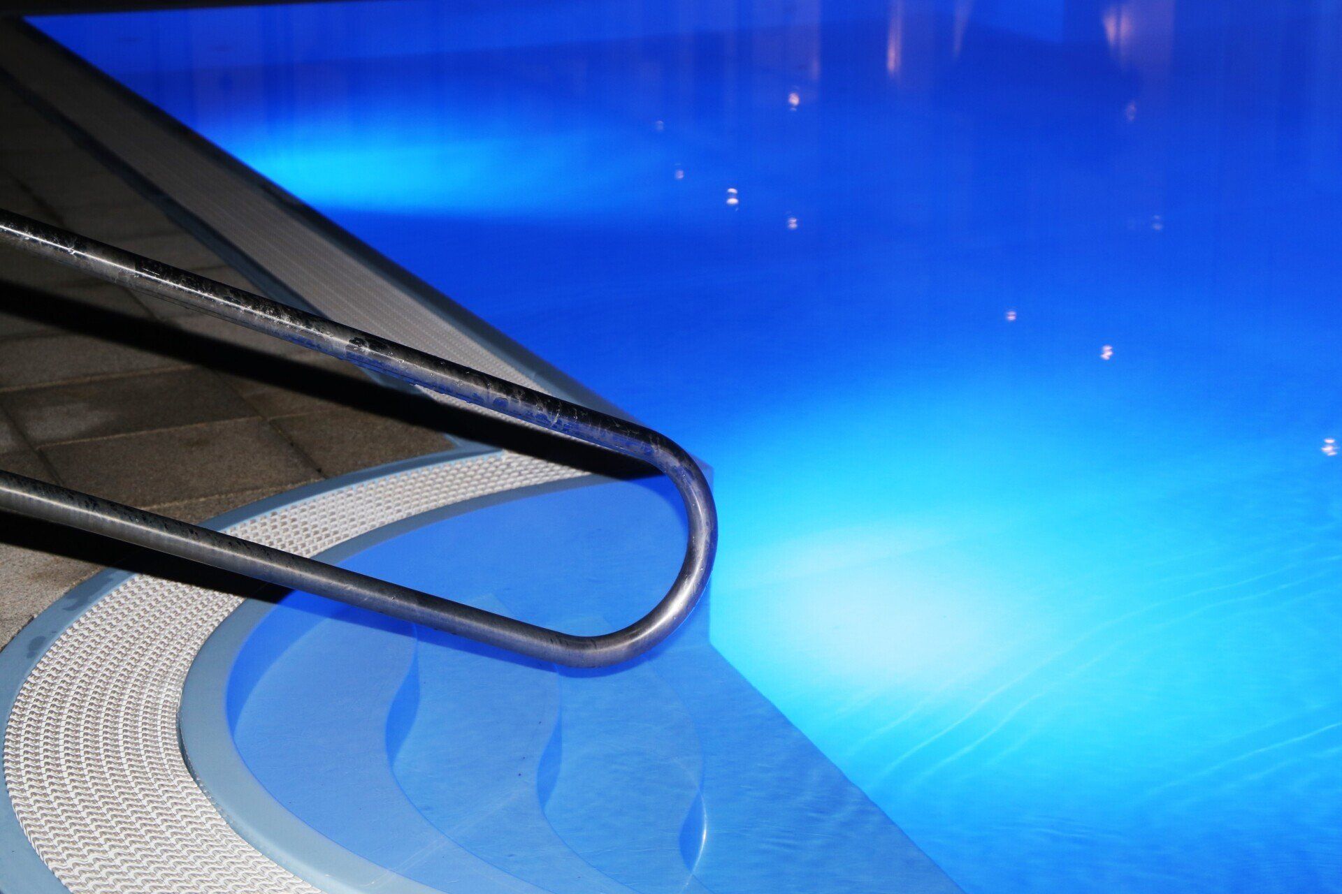 A swimming pool is lit up at night with blue lights